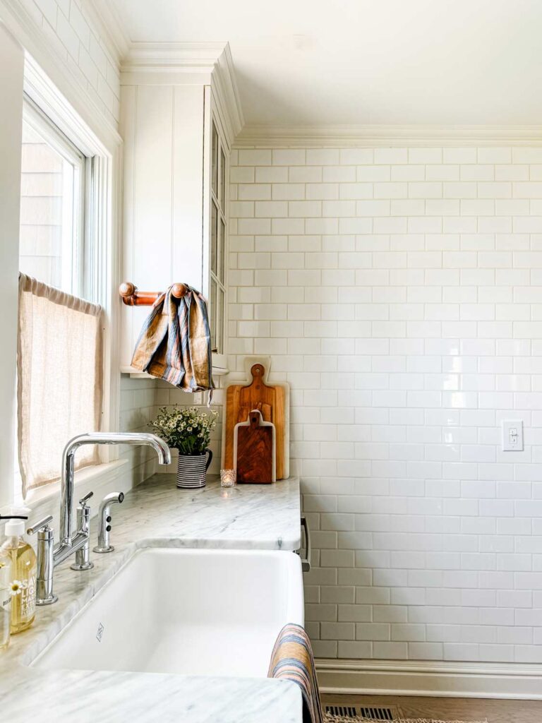 Vintage french hook with a stripe towel, cutting boards, sink with chrome faucet.