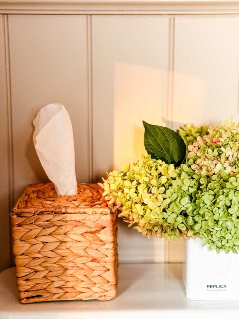 A seagrass tissue box cover and hydrangeas in a white tin.