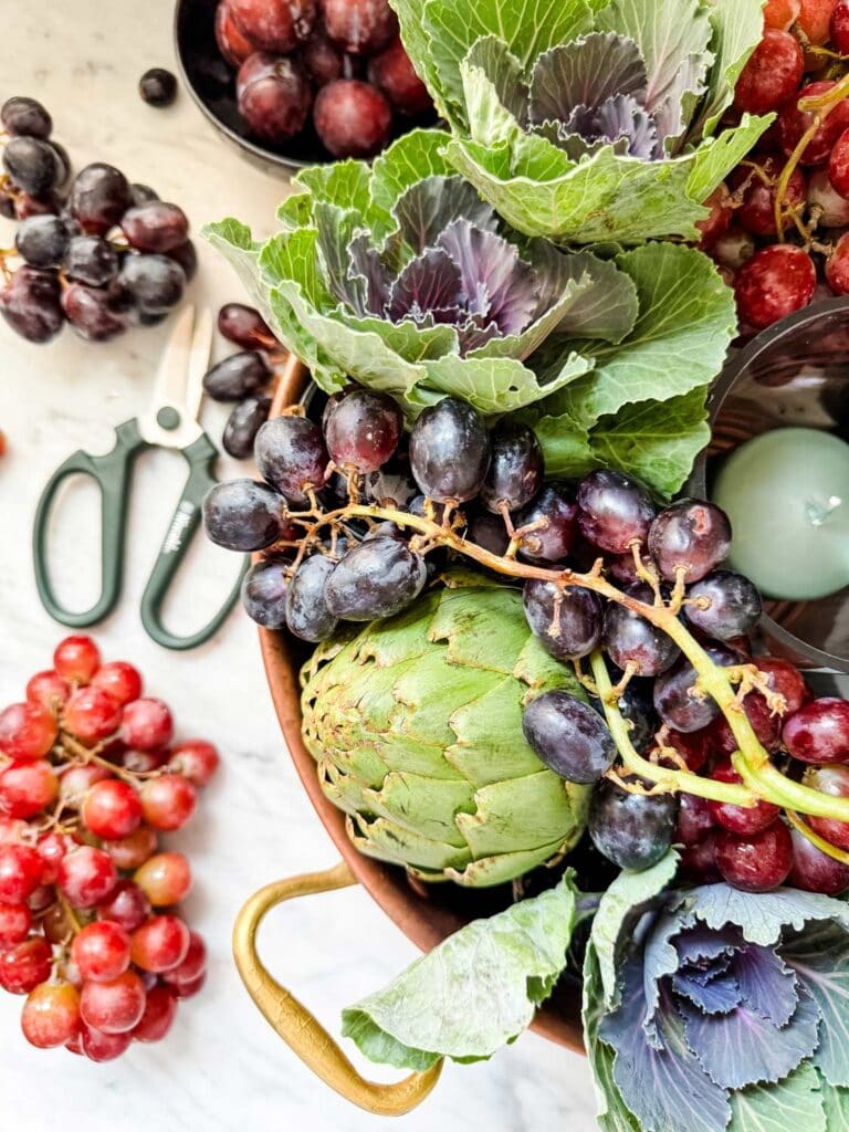 Grapes, artichokes, ornamental cabbage, candle, scissors. 