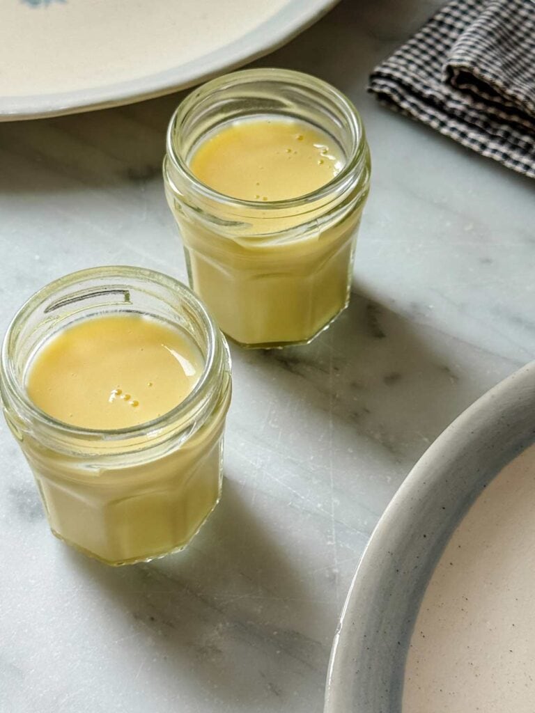 Crème Anglaise has been made and poured into Bonne Maman jam jars for served with a caramelized apple and Dutch Baby pancake.