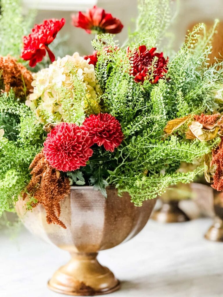 An iron vase has a large bouquet of flower's from Trader Joe's.