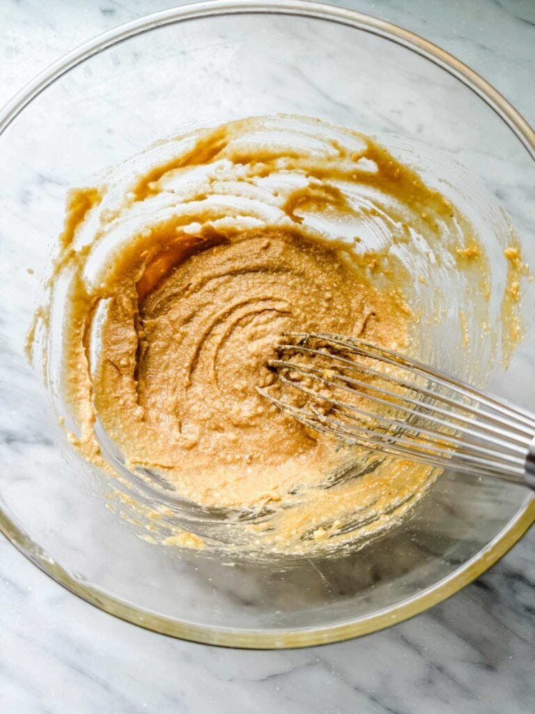 A glass micing bowl with batter and a whisk in the bowl.