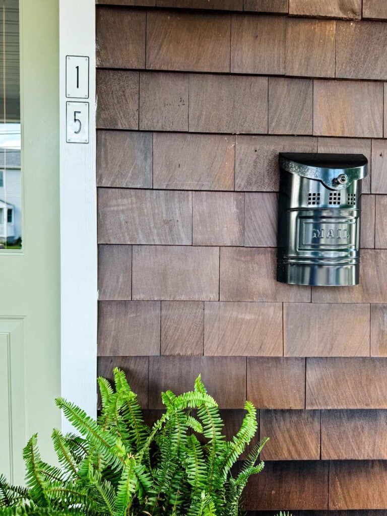 A freshly painted front door with house numbers next to it.