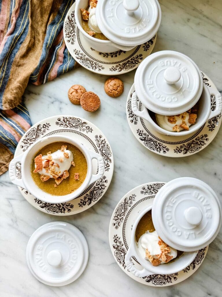 Pumpkin Spice Pot de Creme with Whipped Cream on Top - small Staub pots on brown floral plates with small cookies in wood bowls as topping. 