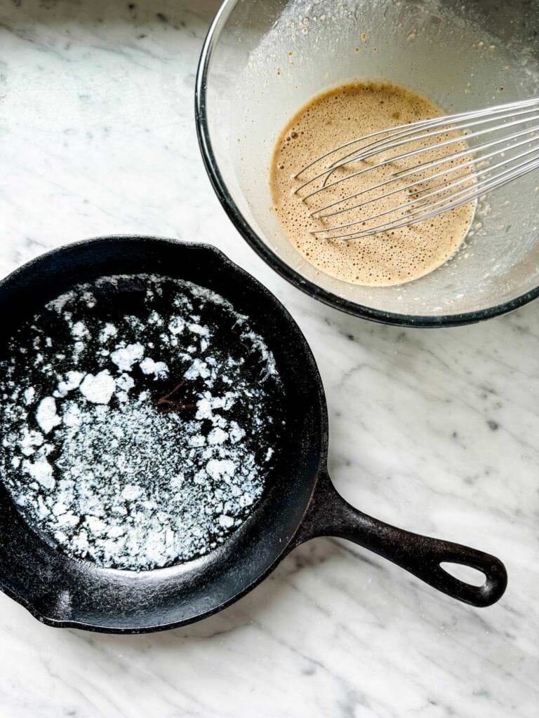 Butter has been melted in a cast iron skillet and the batter is ready to be poured into the skillet for making a Dutch Baby pancake.