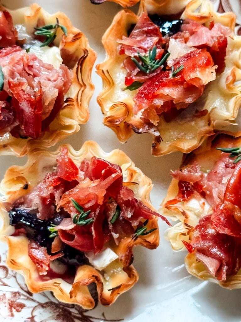 Brie and crispy prosciutto appetizers topped with fresh thyme.