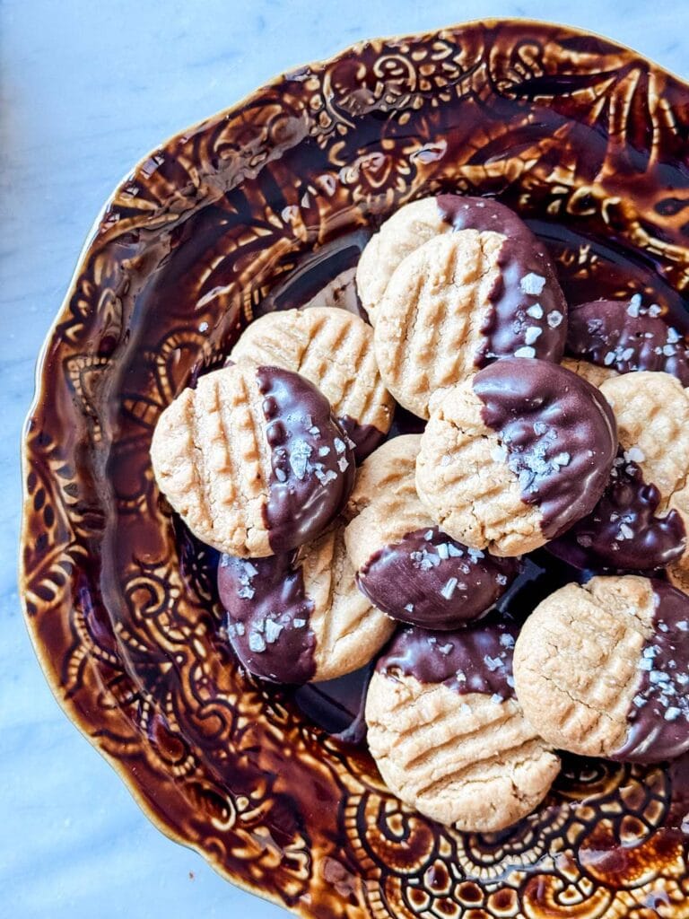 Peanut butter cookies half dipped in chocolate on brown plate.