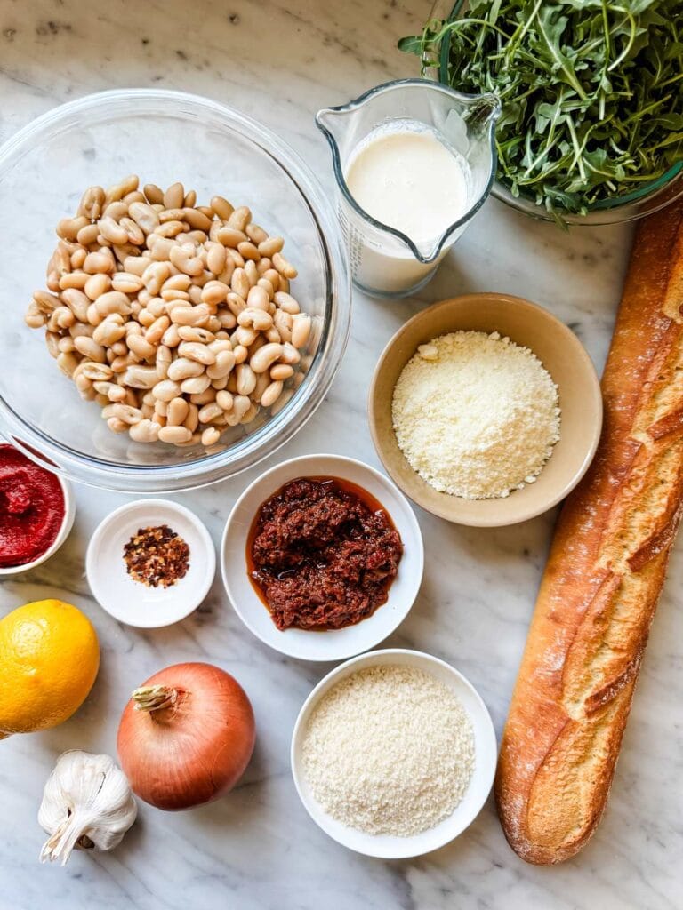 All the ingredients, including a baguette, are measured and ready for making spicy tomato beans and greens.