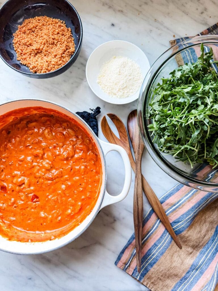 Spicy tomato beans have been prepared and now the arugula salad needs to be tossed.