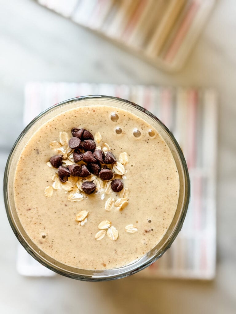 A single healthy date protein shake is topped with a pinch of oats and a few mini chocolate chips.