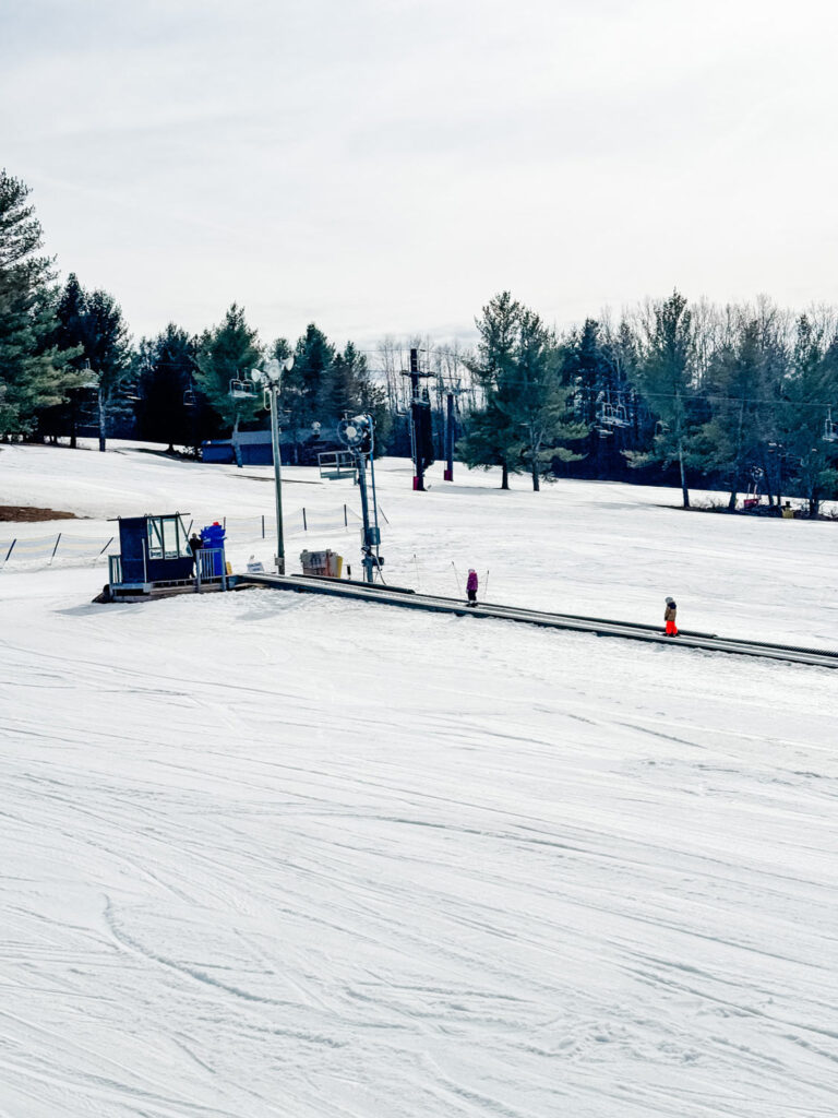 A magic carpet lift with two young kids riding to the top of the hill.