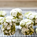 Matcha crinkle cookies are stacked on a wire cooling rack.