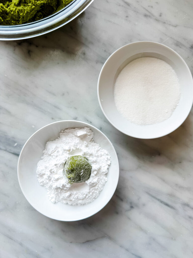 After the cookie dough balls have been rolled in granulated sugar, they are rolled in powdered sugar.