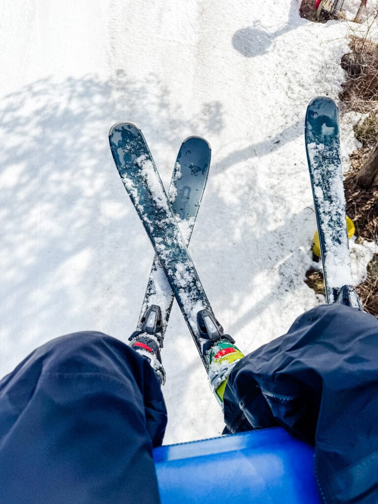 Two sets of legs and skis are dangling on the chairlift.