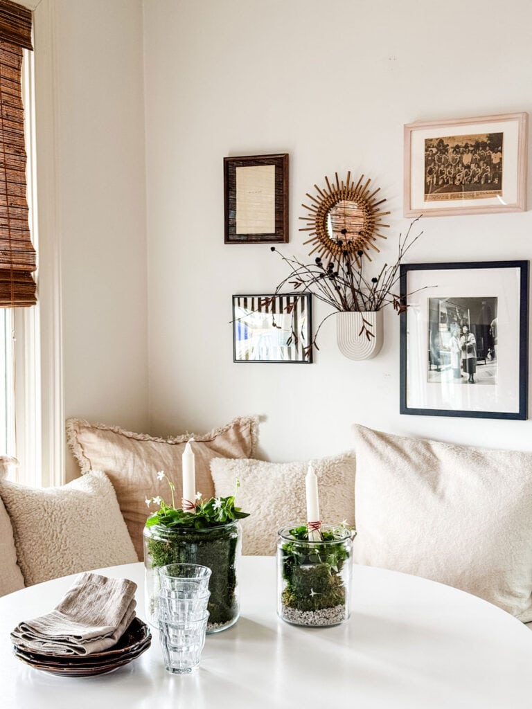 Glass jars with shamrock plants, whote stones, candles on a Saarinen table.