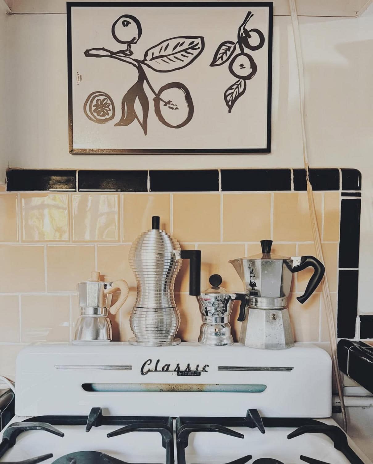 Old stove with art above. stainless steel coffee pots.