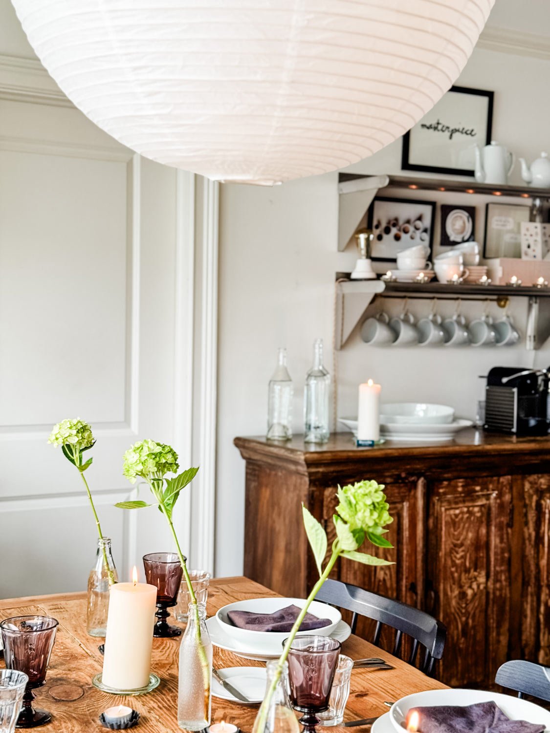 Mix of flatware for a Frnech finner party in a working glass nbext to Duralex glasses, tea lights, bowls, napkins on stacked plates, with HAY modern pendant.