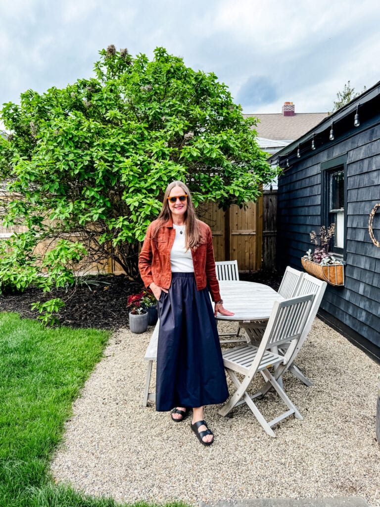 Woman wearing poplin black skirt, linen jacket with white tee.