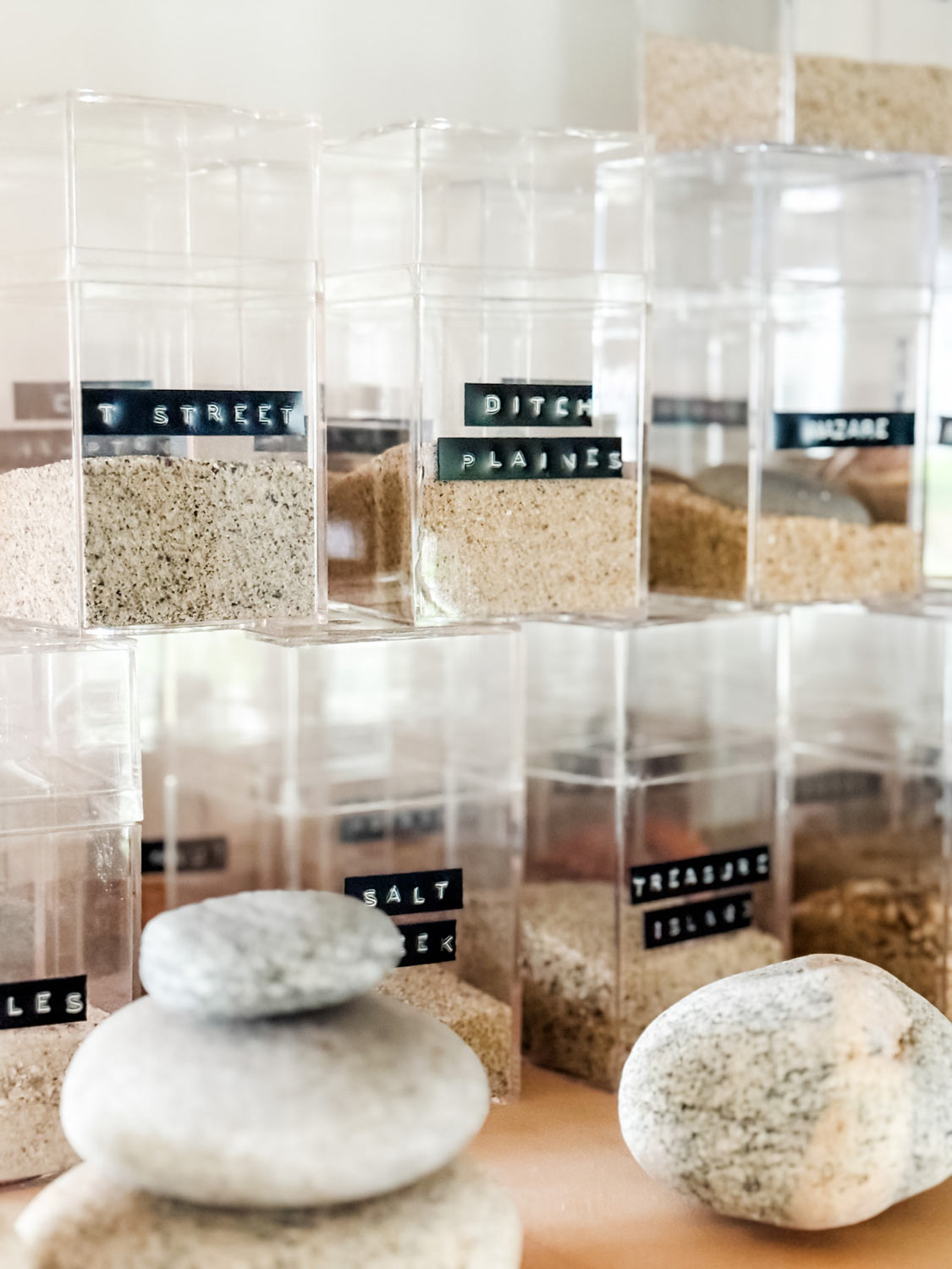 Clear boxes with sand and dymo label with name, and rocks.