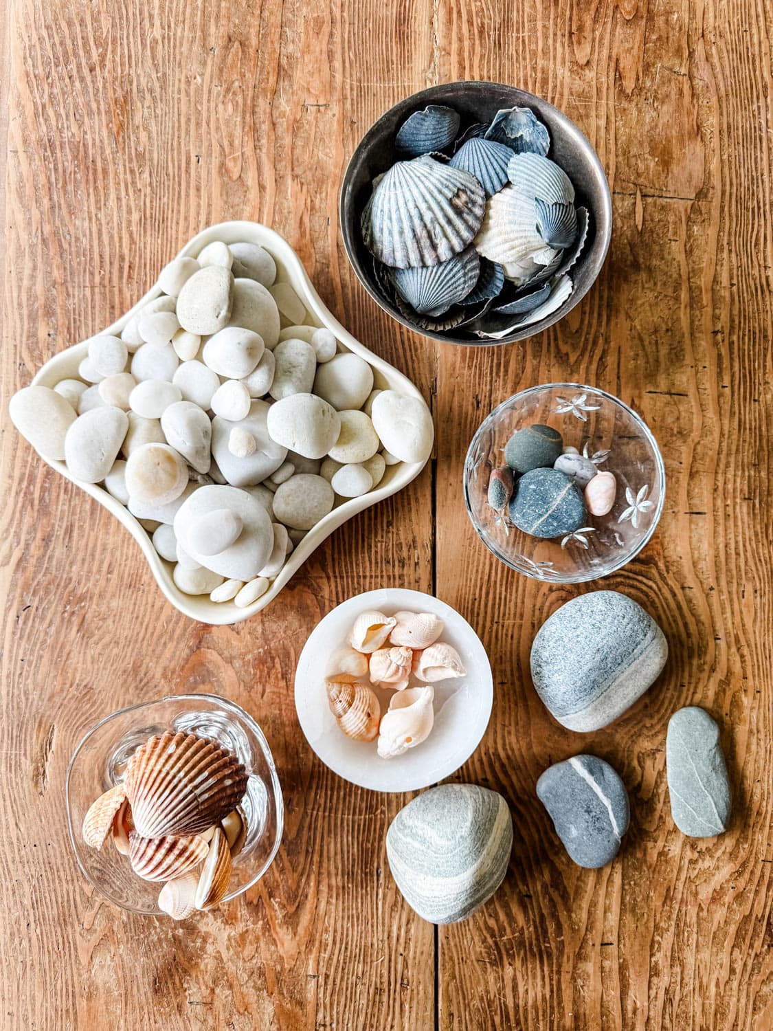 Bowl of rocks, shells, rocks on wood table.