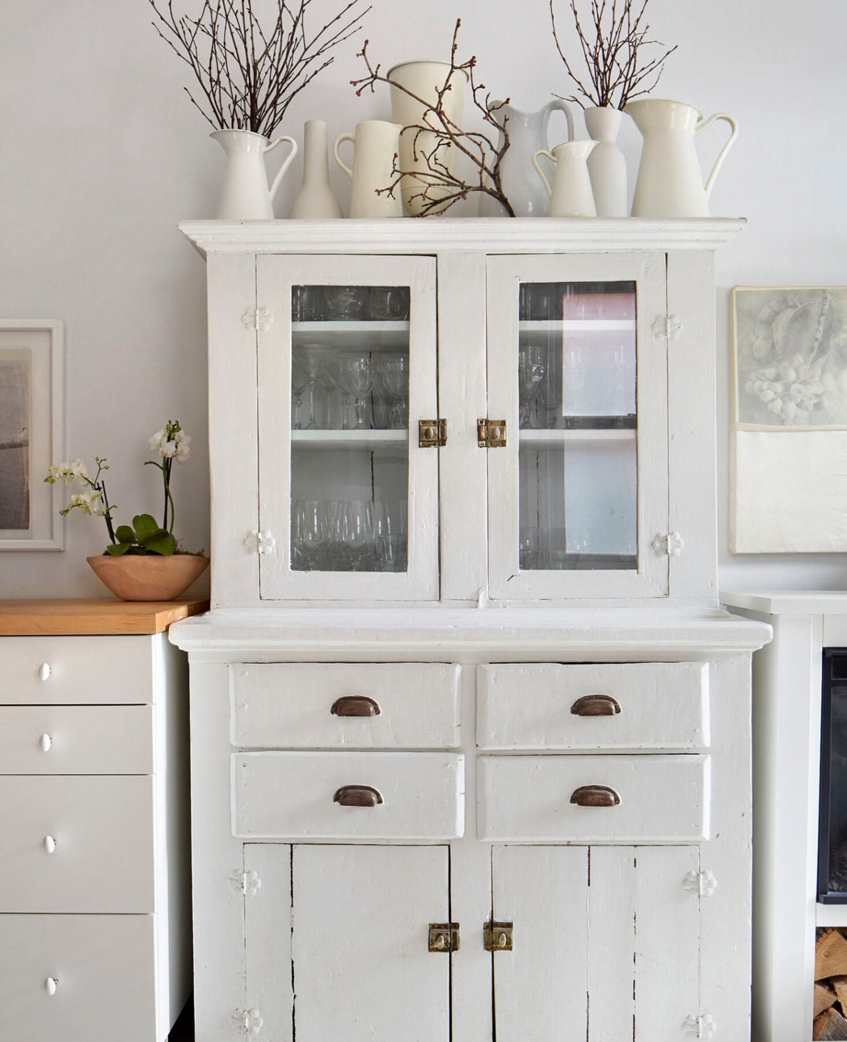 White hutch with white pitcher on top wiht branches.