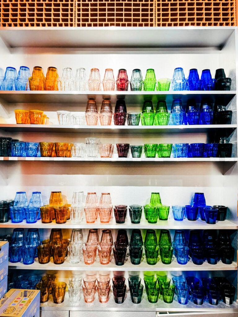 A wall with shelves full of Duralex glasses in different colors on display at the small Duralex store in Paris.