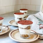 Easy tiramisu served in small Duralex cups on brown plates.