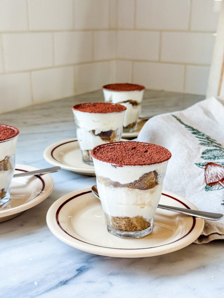 Easy tiramisu served in small Duralex cups on brown plates.