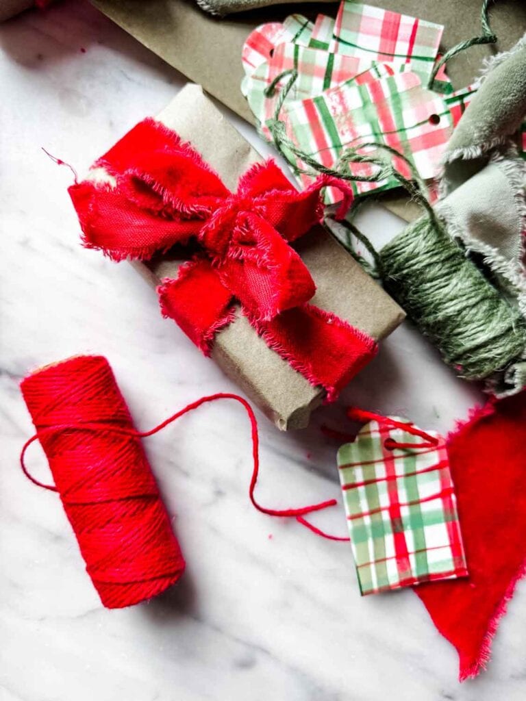 Red and green watercolor painted tags with red and green twine. Roll of green paper with packages tied up with red velvet ribbon.