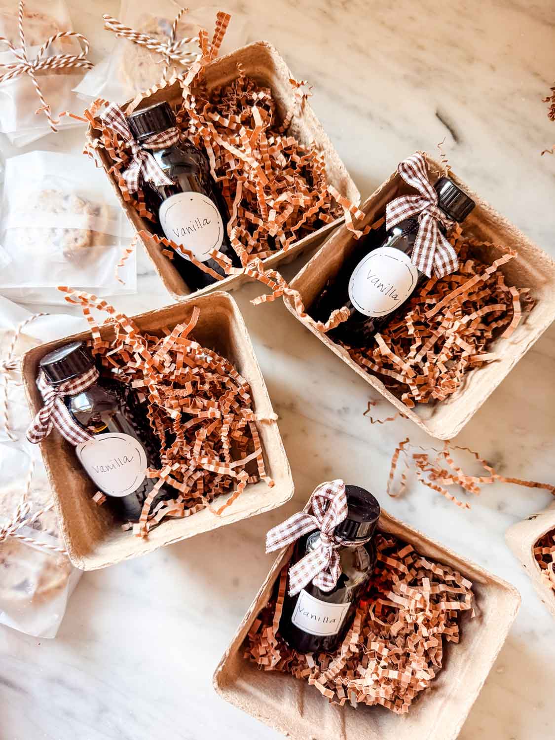 Berry baskets with amber bottles of vanilla and small package of shortbread cookie toed up wiith bakers twine.