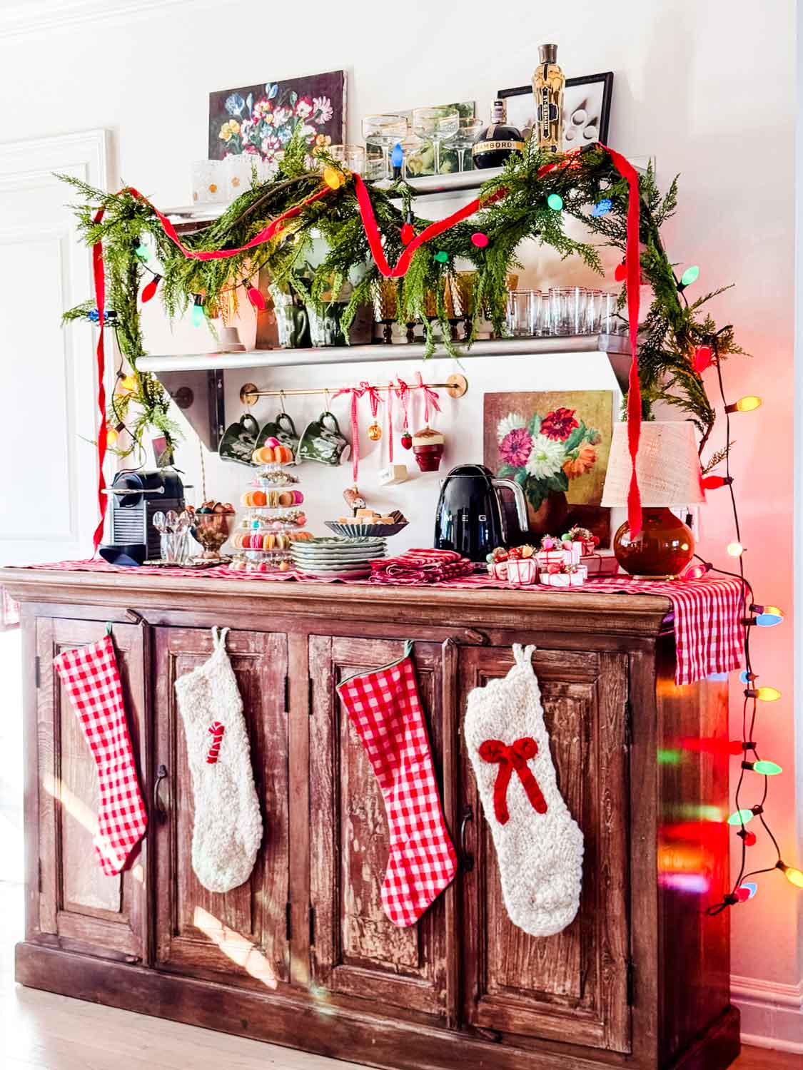 Festive side board set up for holiday entertaining with Christmas stockings, lights, garland.