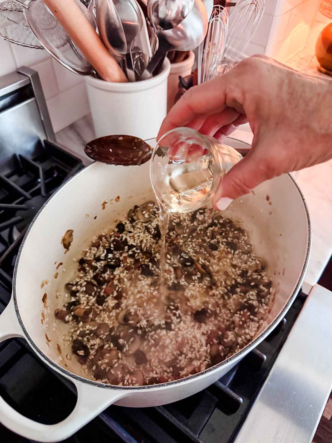 White wine is added to the rice and mushroom mixture to deglaze the pan and add flavor.