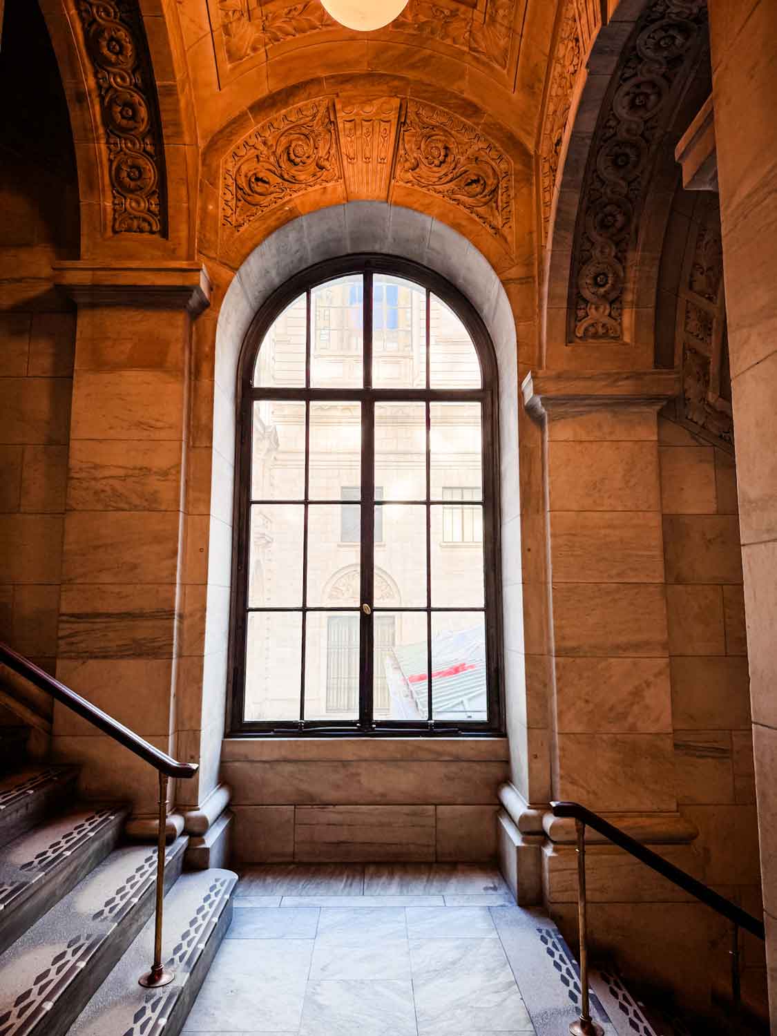 A landing, between the 3rd and 2nd floors, features a huge arched window that lets in a lot of natural light.