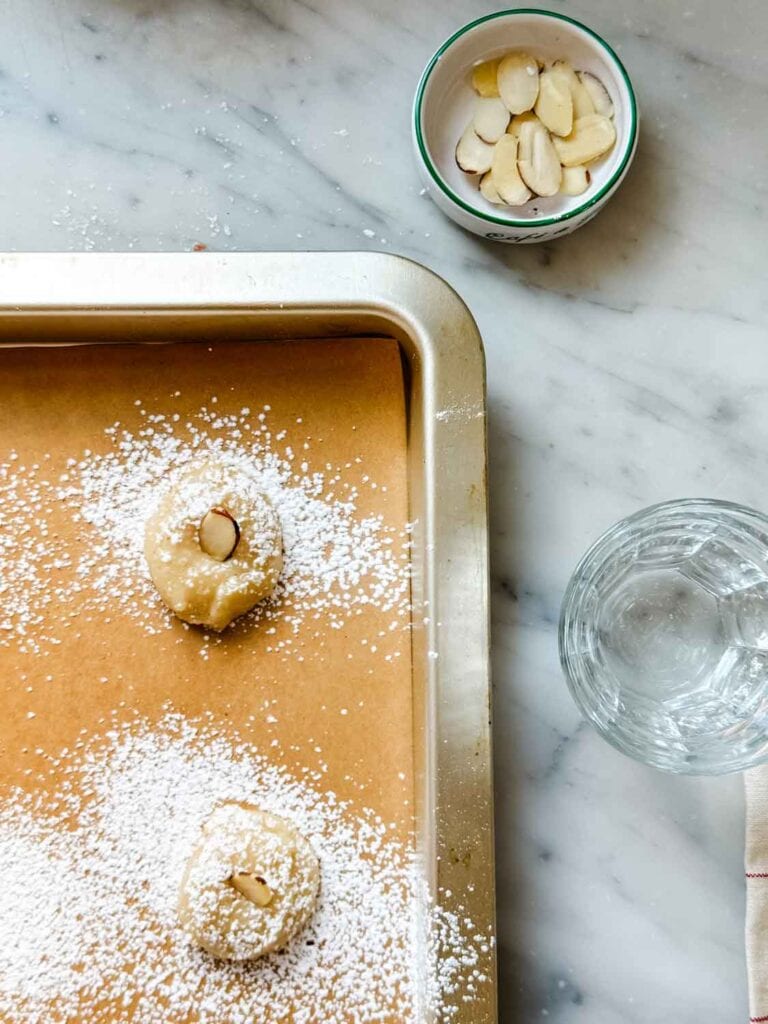 Almond slivers are added in the center of each dusted cookie dough ball.