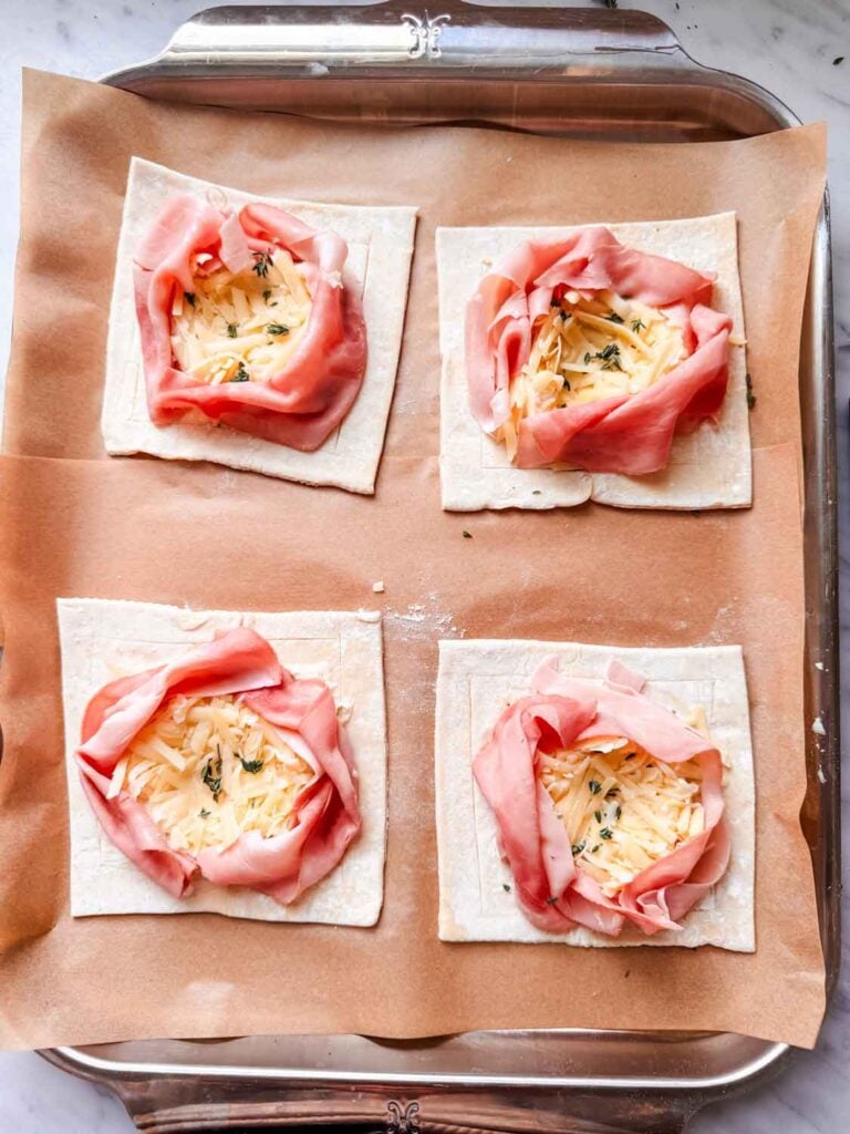 Gruyere cheese is placed on top of the sauce, sprinkled with thyme, and flattened with the back of a spoon.