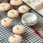 Baked macarons with slivered almonds are cooling on a wire rack.