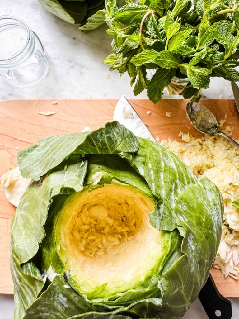 A head of cabbage hollowed out on a wood cutting board.