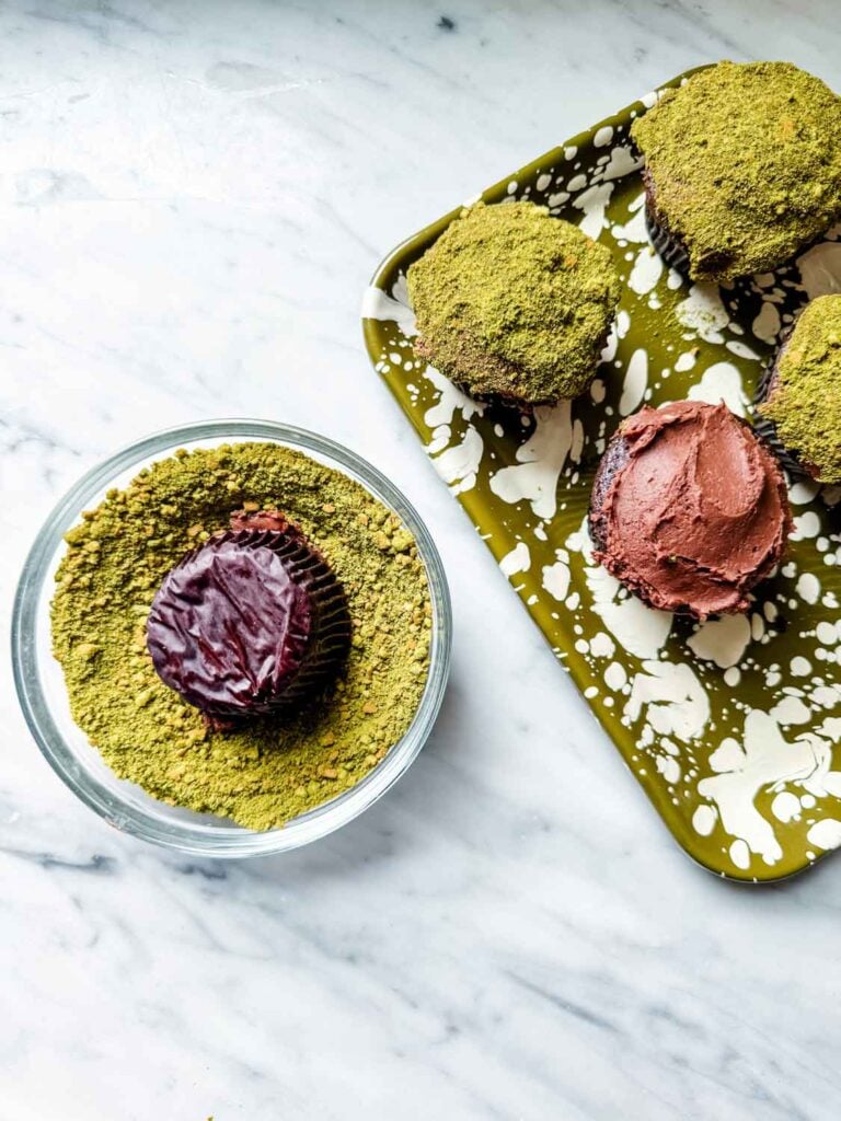 Chocolate cupcakes with matcha moss, chocolate bunnies on green splatter tray. Chamomile flowers.