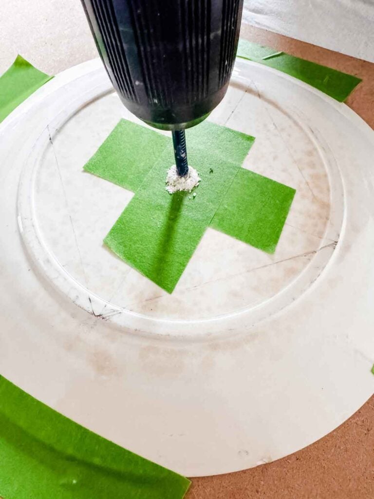 Tape in a plus formation with dot in the center of the tape on the plate, drill showing that it is being drilled.