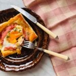 Puff pastry croque madame is served on small brown plates.