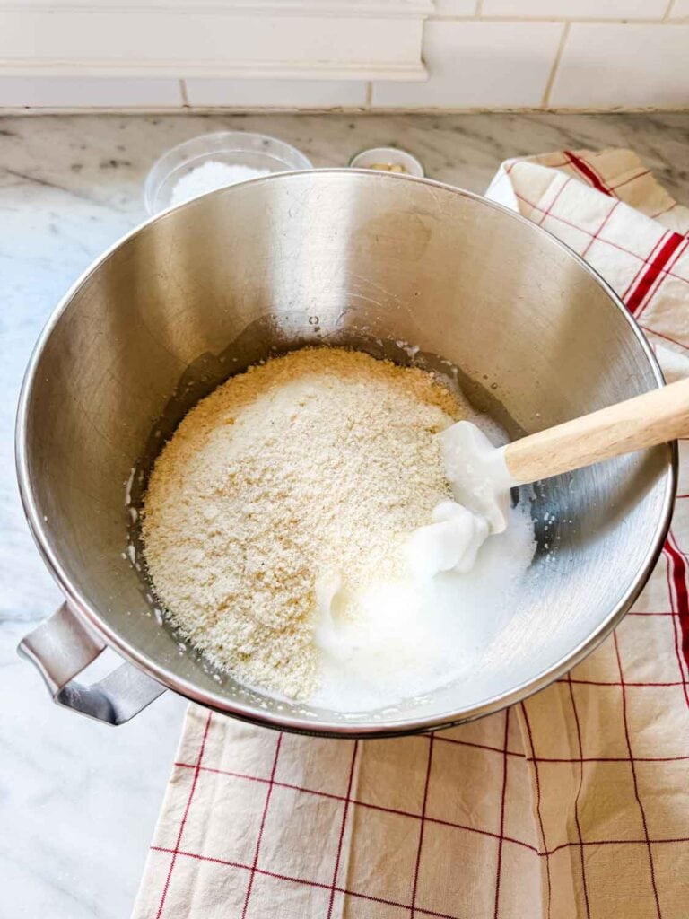 The dry ingredients for making macaron cookies are being folded into the whipped egg whites.