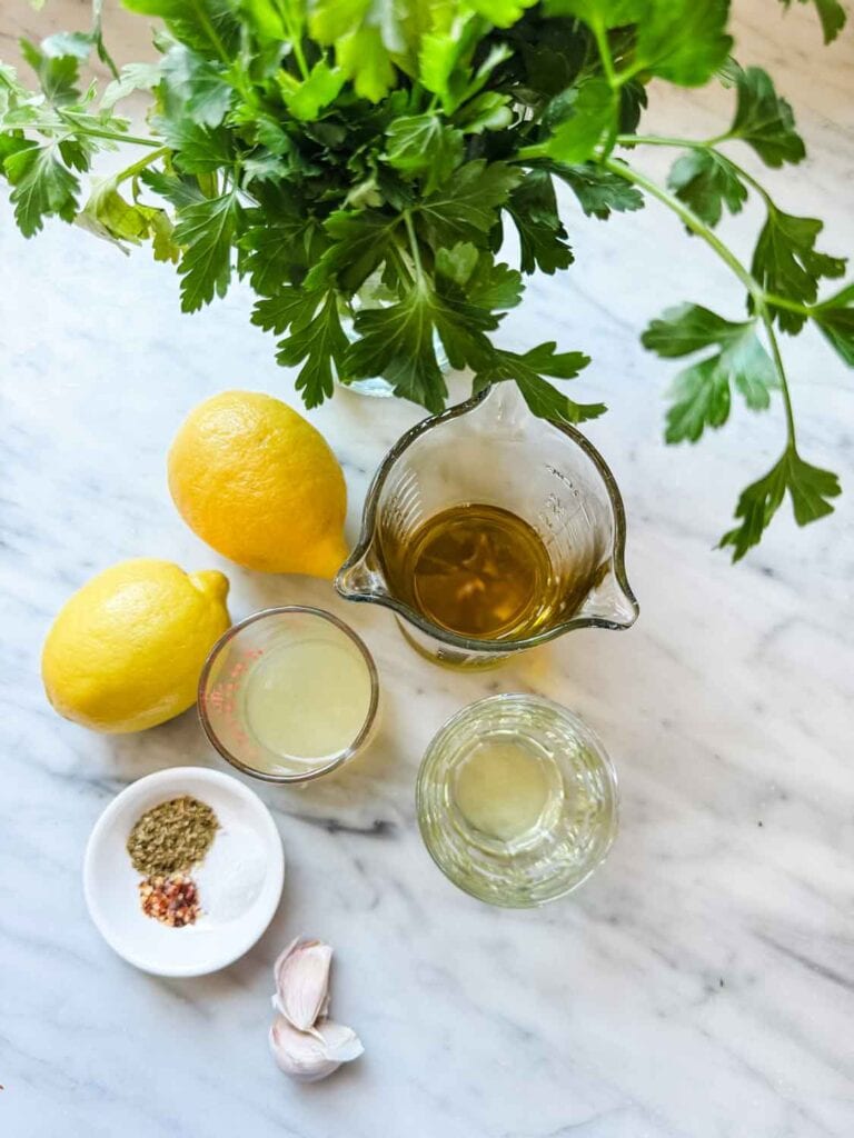 Fresh parsley, 2 lemons, small glass containers of olive oil, lemon juice, 2 garlic cloves, dish of spices.