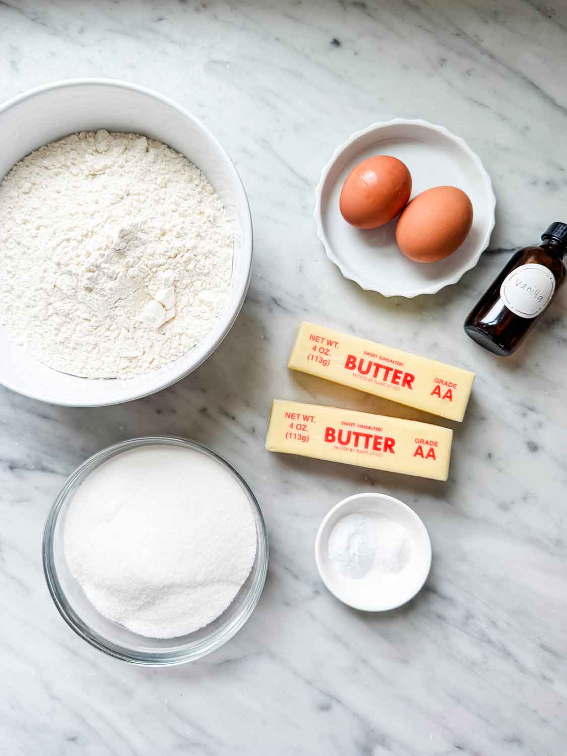 Eggs, butter, flour, salt, sugar, baking soda, and vanilla extract have been measured, placed in containers, and are ready for making cookie dough.