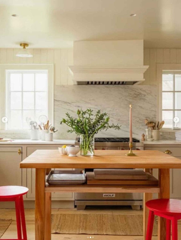 Kitchen with simple free standing island with two red stools. 