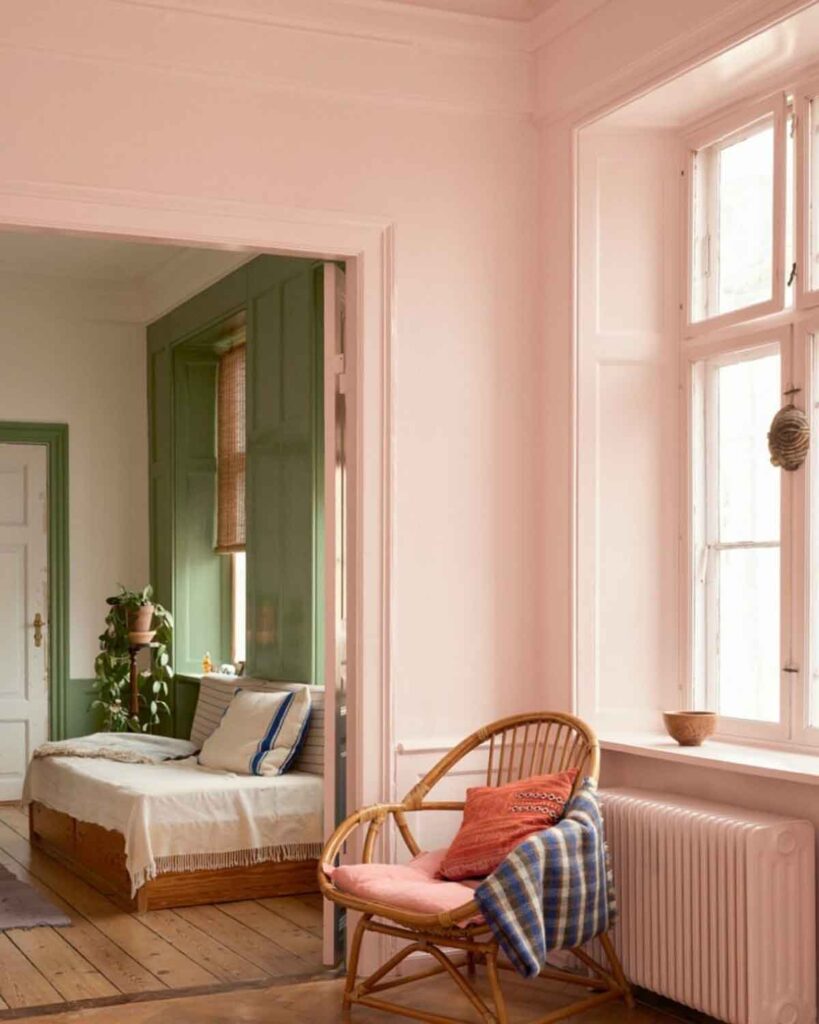 Pink walls and green walls, a chair with a cushion and a plaid throw on the arm.