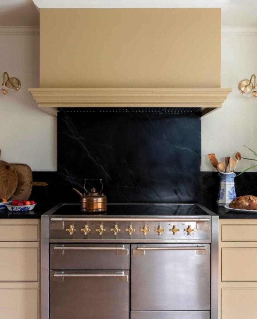 A stainless steel oven is with a large hood is the centerpiece of this kitchen.