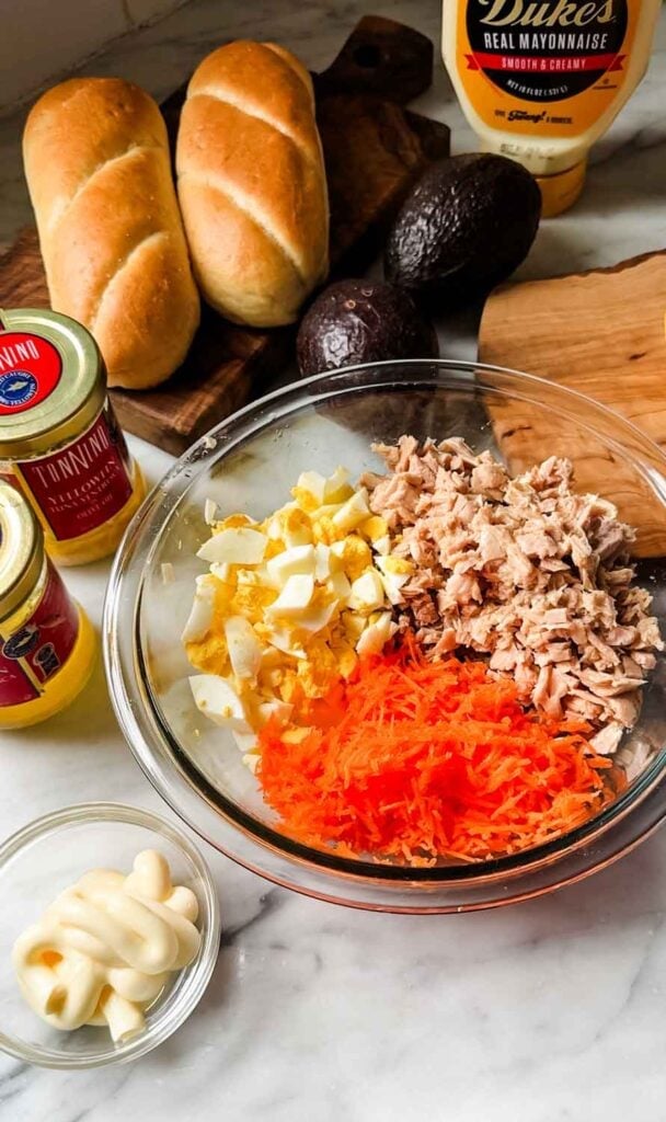 Shredded carrots, tuna, and chopped eggs are in a bowl, ready for mixing and making tuna sandwiches.