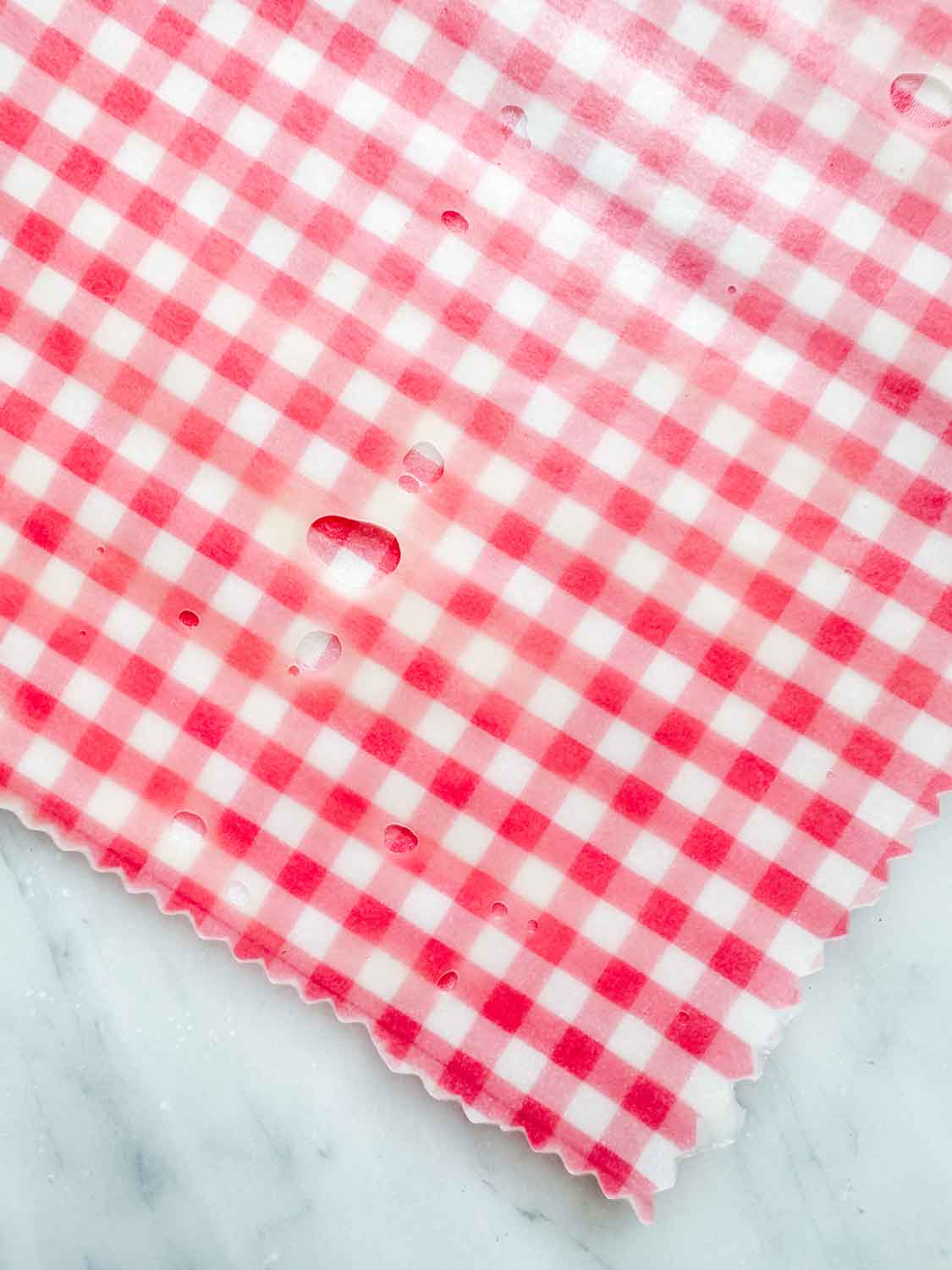 A piece of fabric has been unevenly coated with beeswax. To fix this problem, you put the fabric back in the oven, remelt the wax, and spread it evenly with a paintbrush.