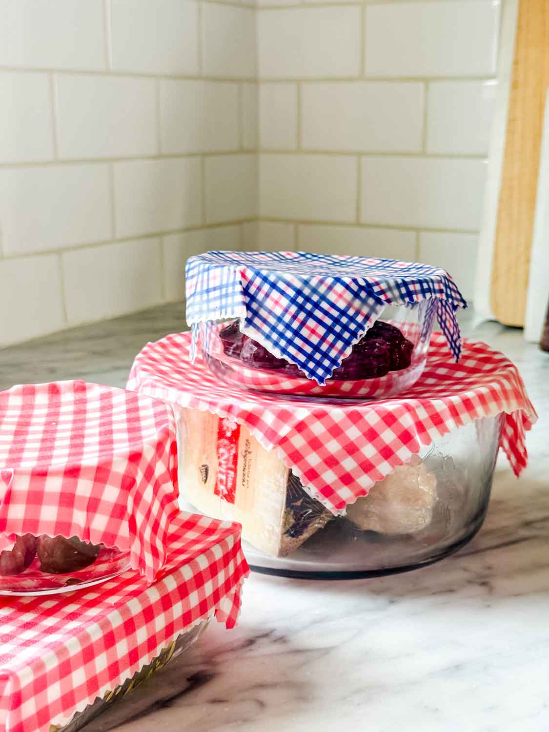 Containers of food are covered with beeswax food wraps and they're sitting on a kitchen countertop.
