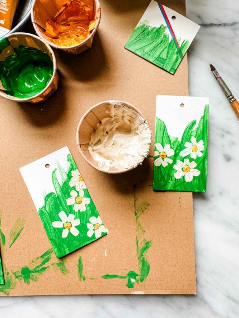 Tags, paints, some painted green partially with daisies with yellow centers.